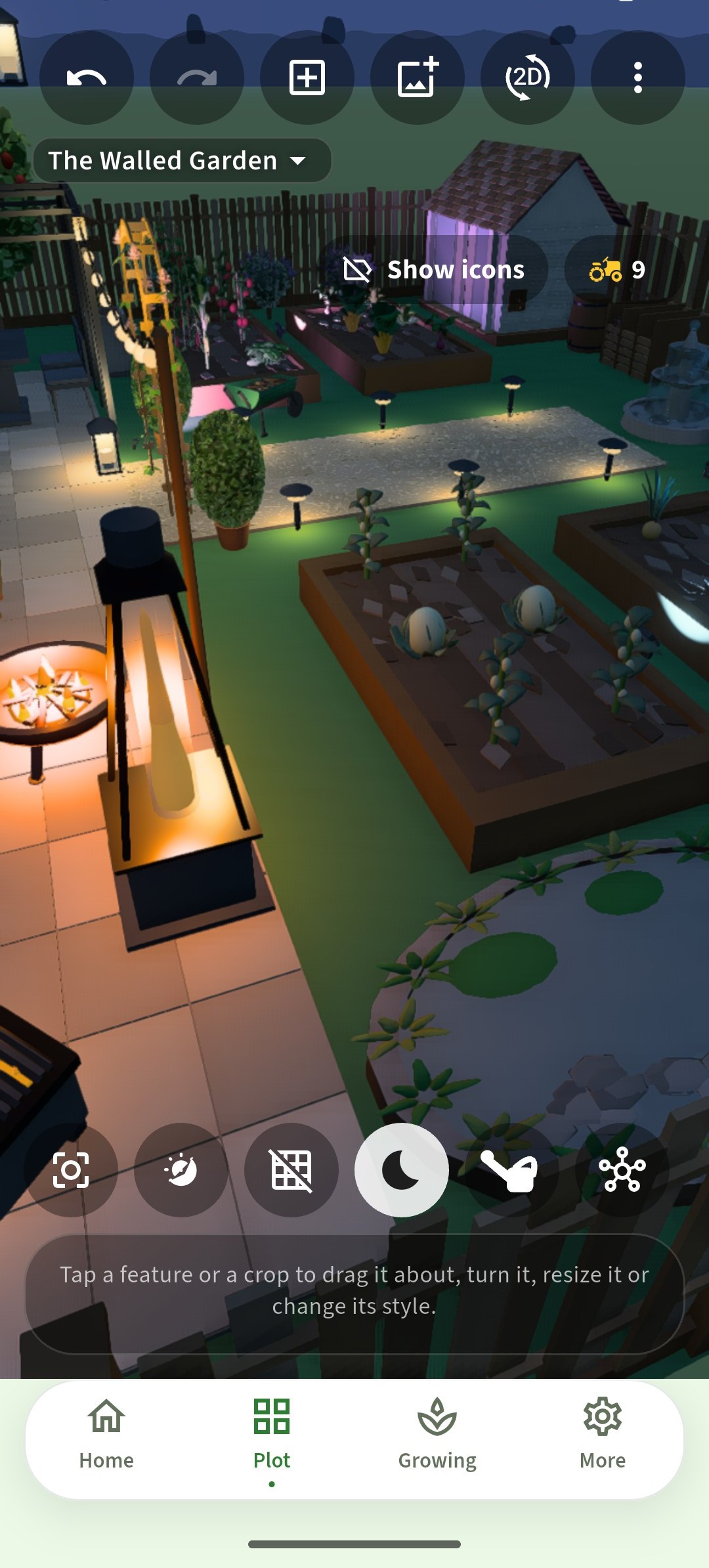 The same walled garden after dark, lit by string lights, path lights and a firepit